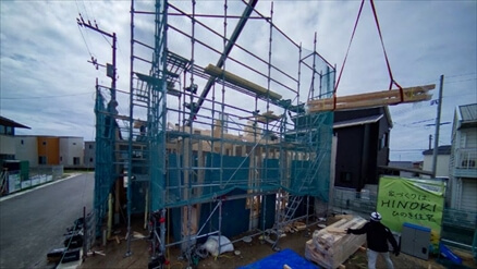足場の中で木材を吊り上げている建方の様子